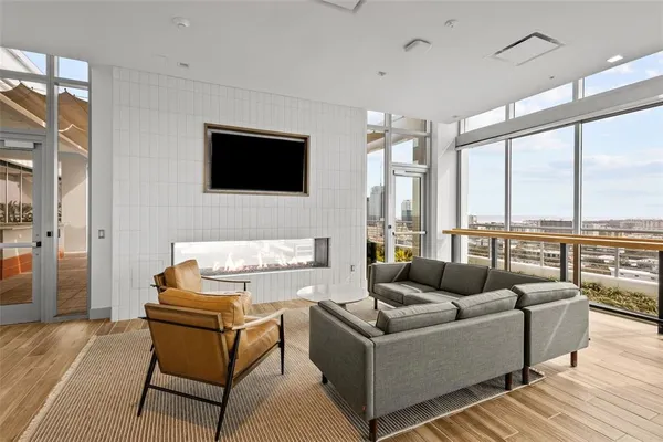 a living room with furniture floor to ceiling window and a flat screen tv