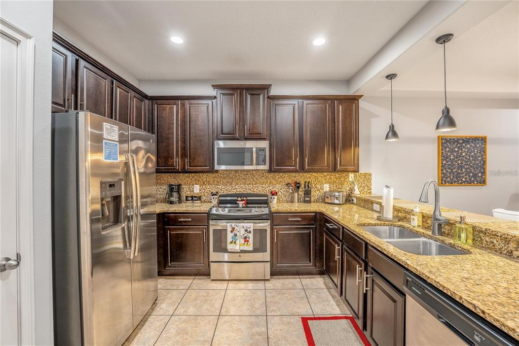 8223 Roseville Road Davenport, FL 33896 - Photo 4 of 17 a kitchen with kitchen island granite countertop a sink stove and refrigerator
