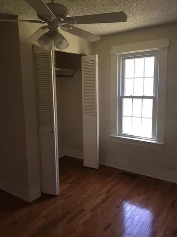 an empty room with wooden floor closet and windows