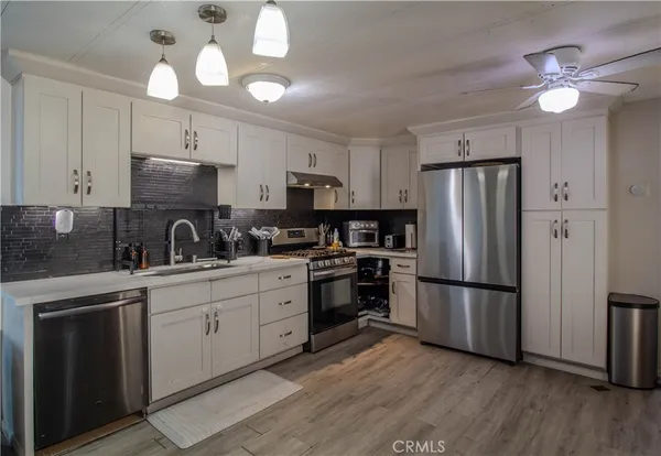 a kitchen with cabinets stainless steel appliances a sink and wooden floor