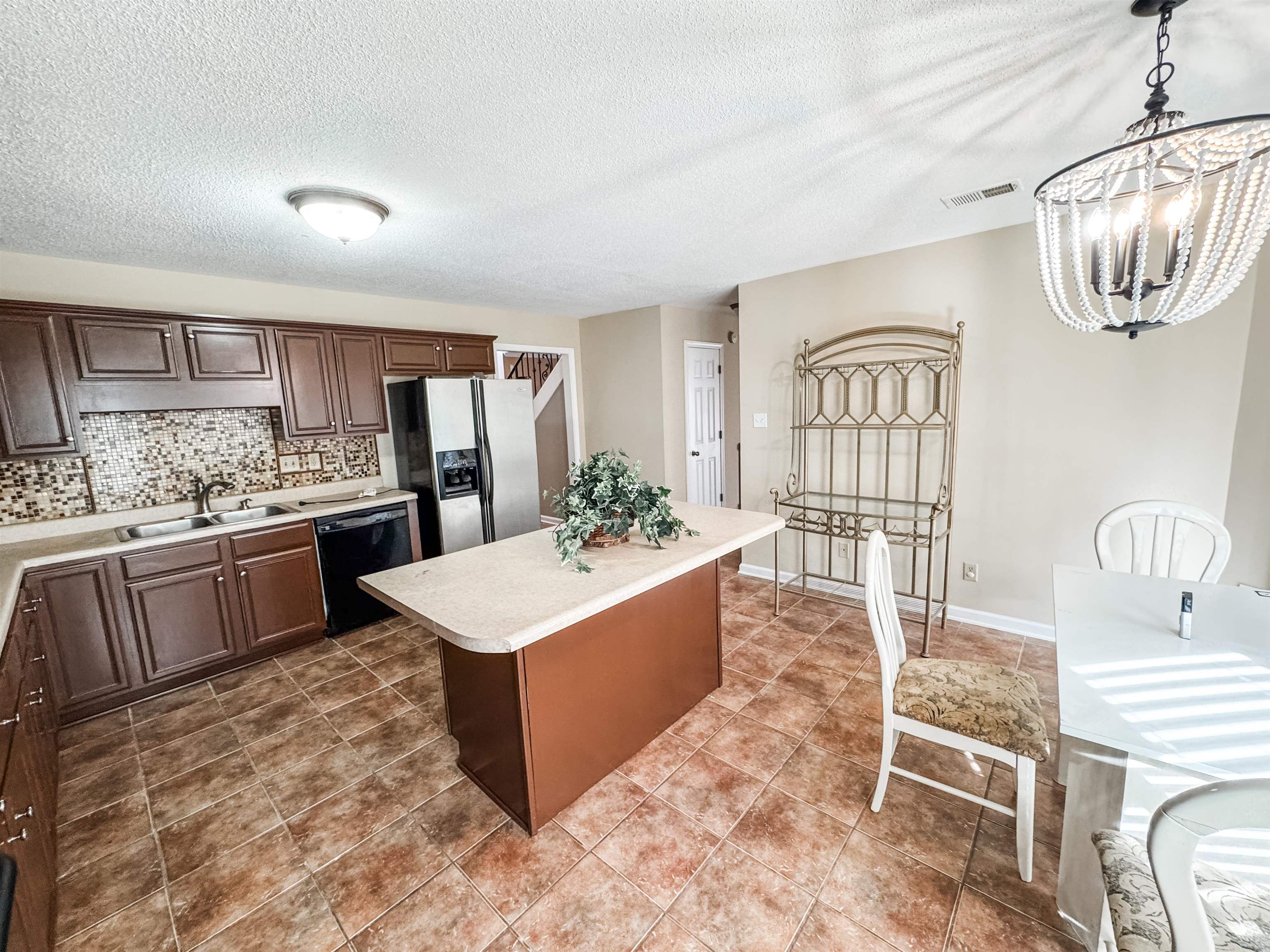 10431 Pilot Rock Road Collierville, TN 38017 - Photo 6 of 15 Kitchen with an inviting chandelier, hanging light fixtures, stainless steel refrigerator with ice dispenser, black dishwasher, and a kitchen island