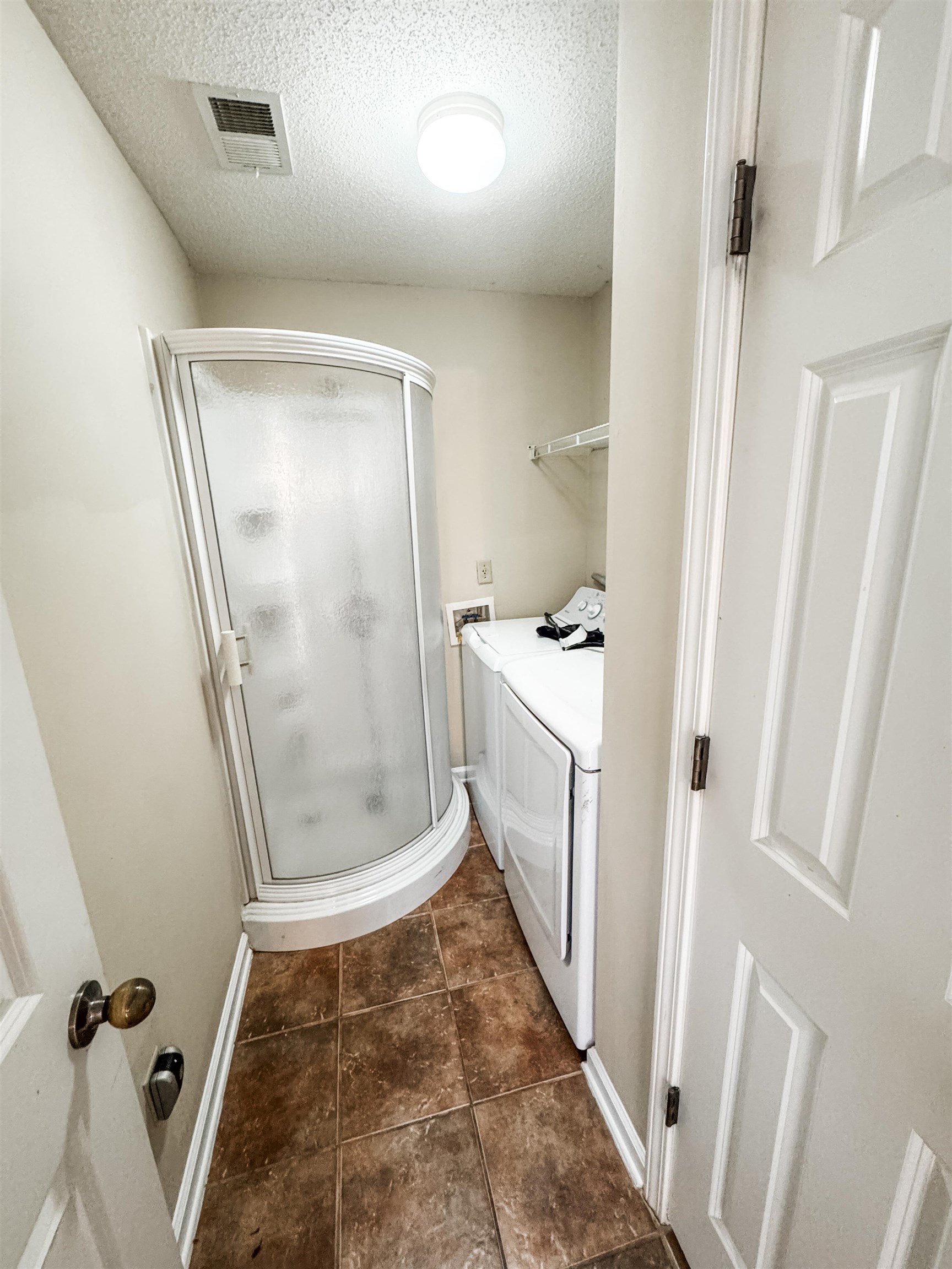 10431 Pilot Rock Road Collierville, TN 38017 - Photo 7 of 15 Clothes washing area featuring dark tile patterned floors, a textured ceiling, and washing machine and clothes dryer