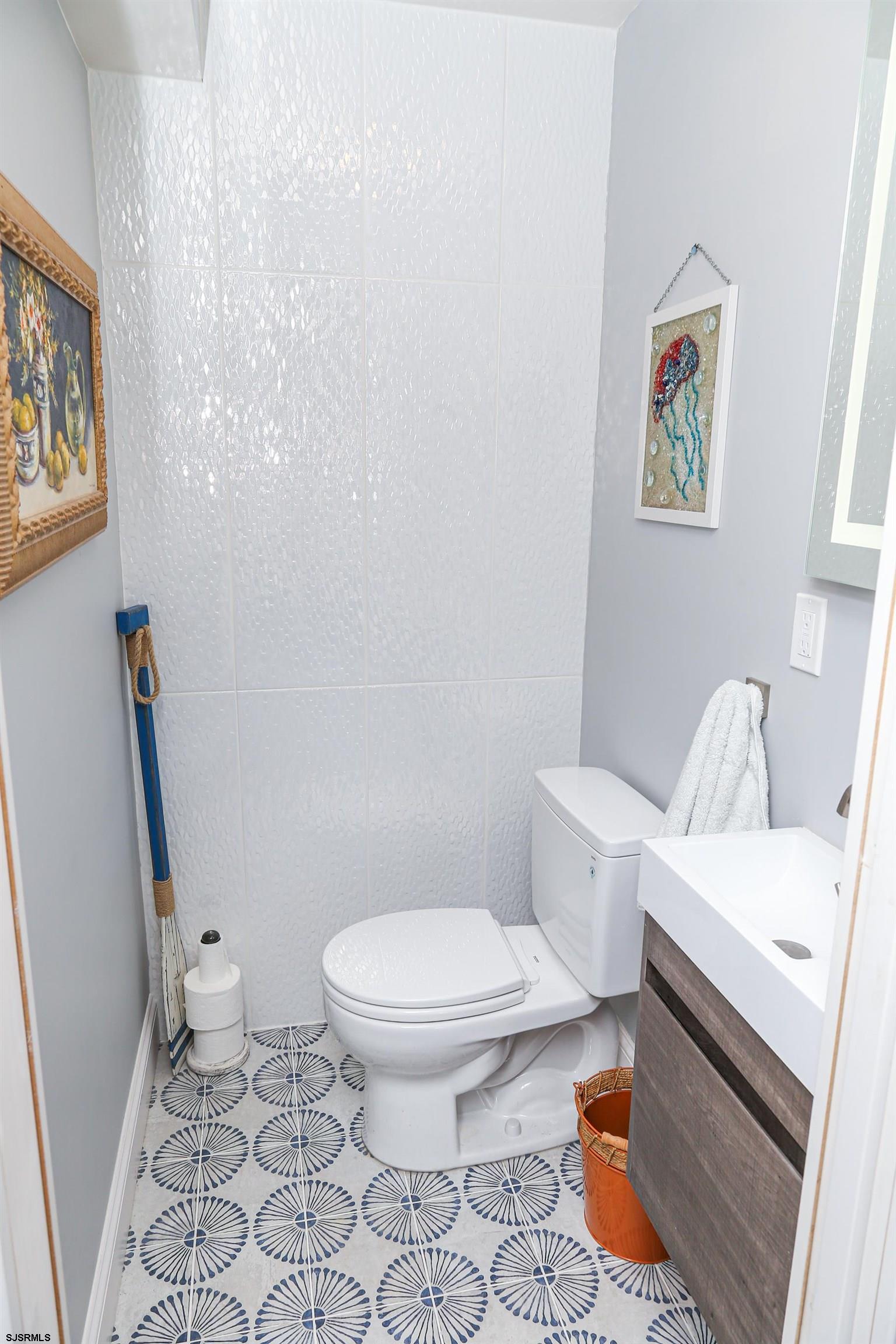 401 37th Street South, Unit 5 Brigantine, NJ 08203 - Photo 19 of 48 a white toilet sitting next to a bathroom sink and a mirror