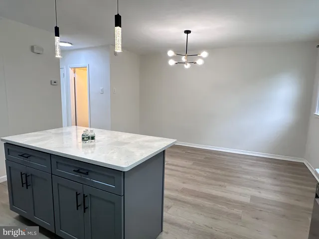 an empty room with kitchen and chandelier