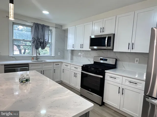 a kitchen with white cabinets and appliances
