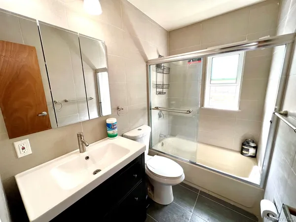a bathroom with a bathtub shower sink vanity mirror and toilet