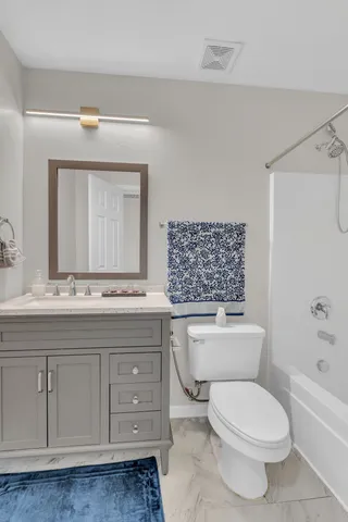 a bathroom with a toilet a sink a mirror a bathtub and vanity