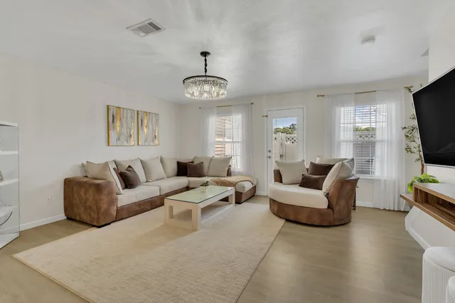 a living room with furniture a flat screen tv and kitchen view
