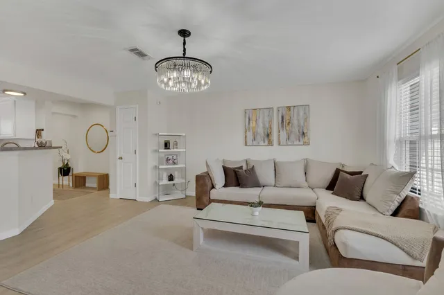a living room with furniture a chandelier and a large window
