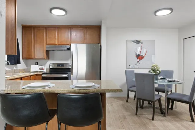 a kitchen with stainless steel appliances a dining table chairs and refrigerator