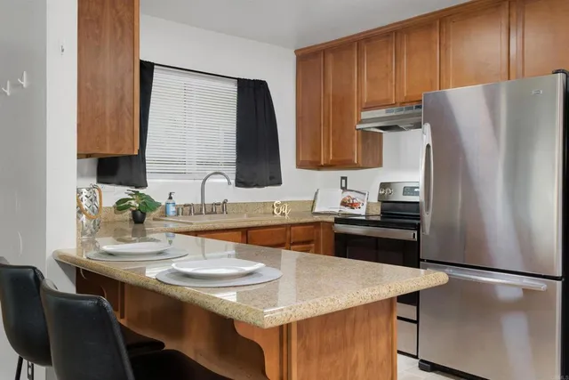 a kitchen with granite countertop a refrigerator stove and sink