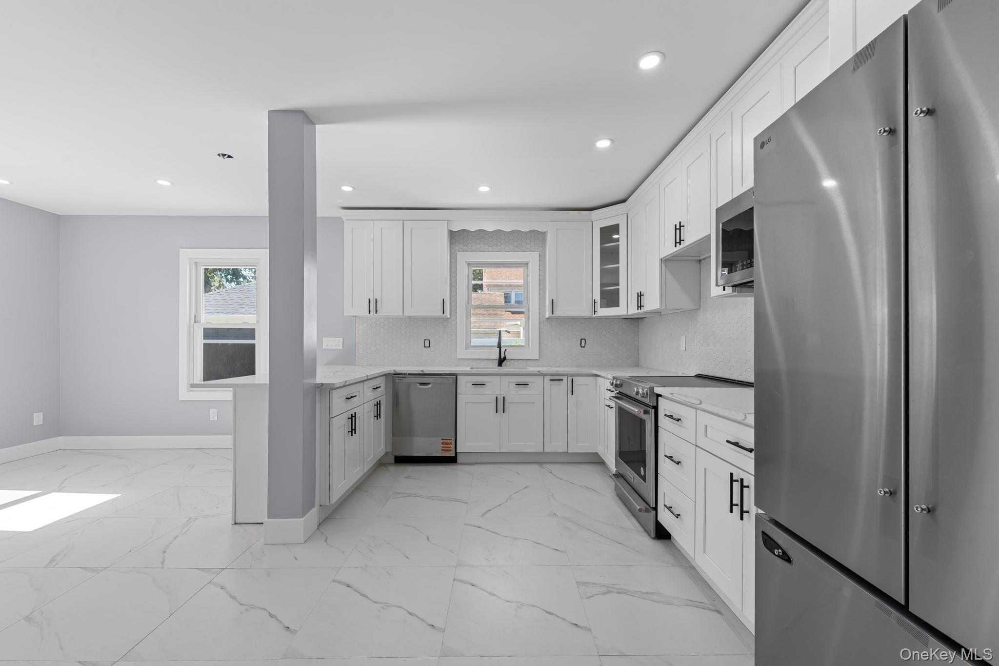 111-32 199th Street Queens, NY 11412 - Photo 3 of 19 Kitchen featuring stainless steel appliances, glass insert cabinets, light marble finish flooring, white cabinets, and backsplash