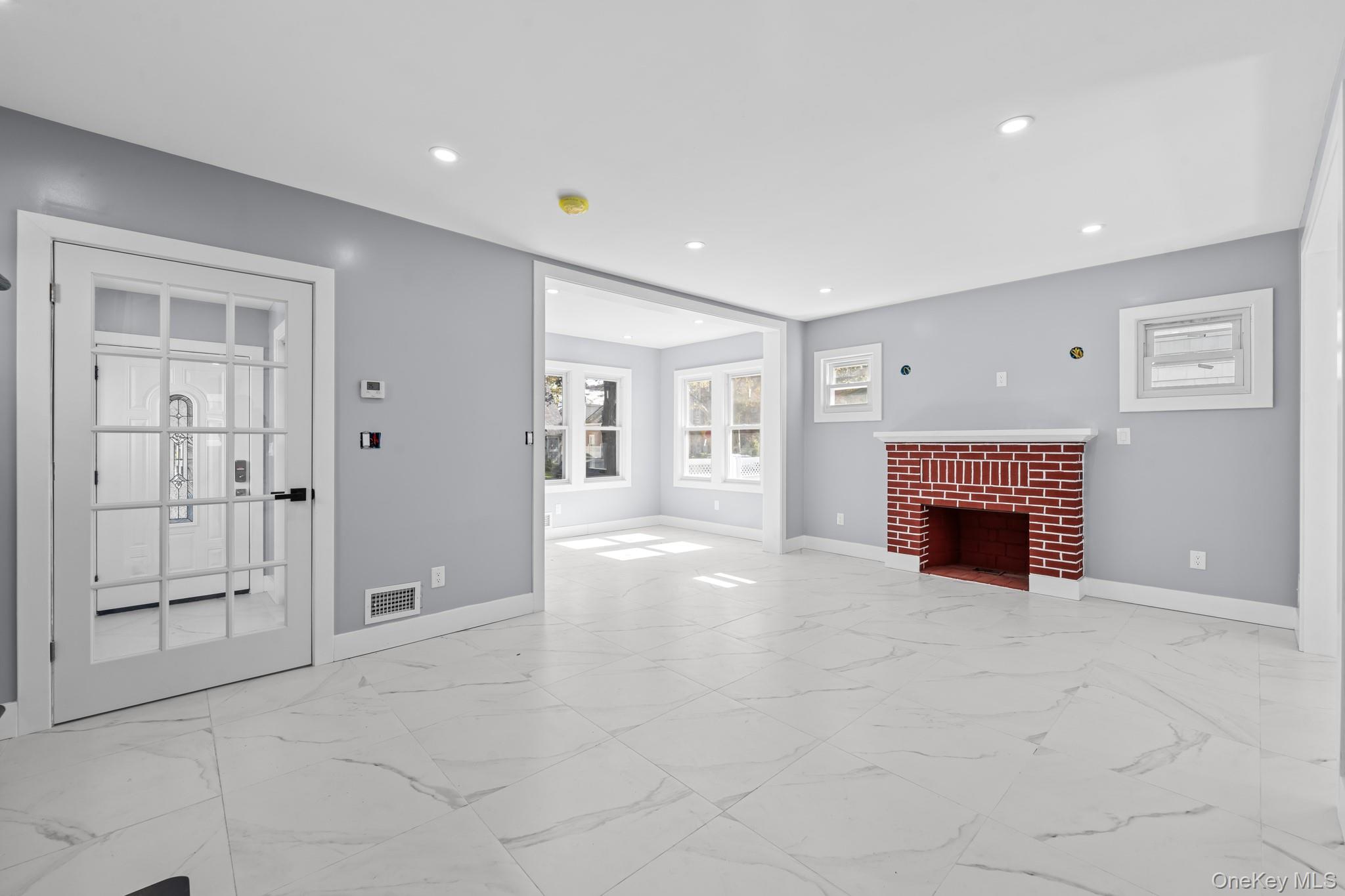 111-32 199th Street Queens, NY 11412 - Photo 5 of 19 Unfurnished living room featuring light marble finish floors, a fireplace, and recessed lighting