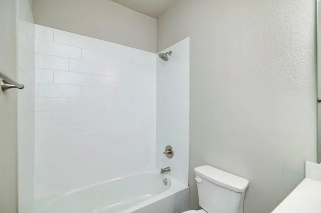 a white toilet sitting next to a bath tub