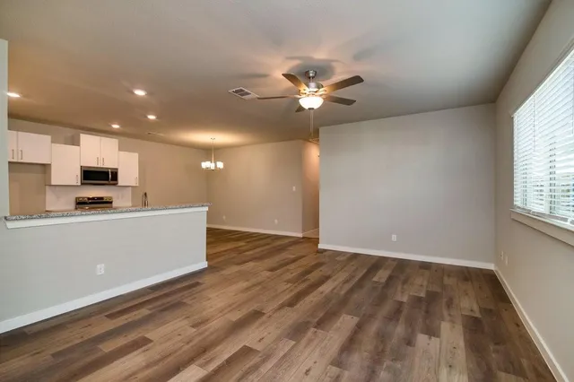 a view of room with kitchen island stainless steel appliances wooden floor and window