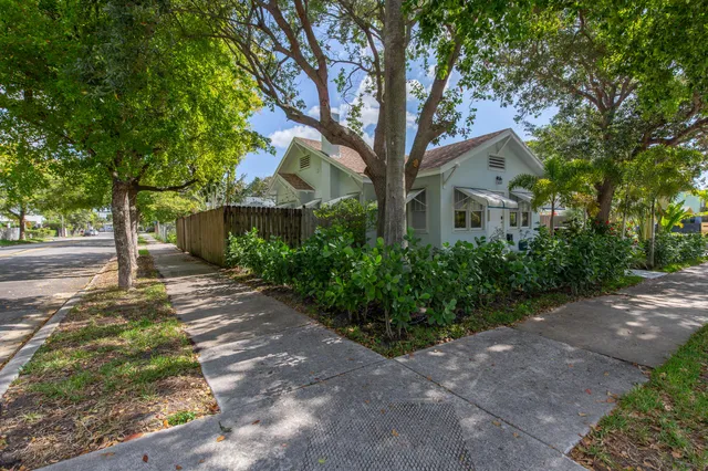 a view of a white house next to a road and trees