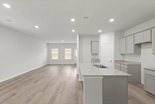 a kitchen with a sink dishwasher a stove and white cabinets with wooden floor