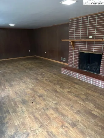 a view of an empty room with wooden floor and a fireplace