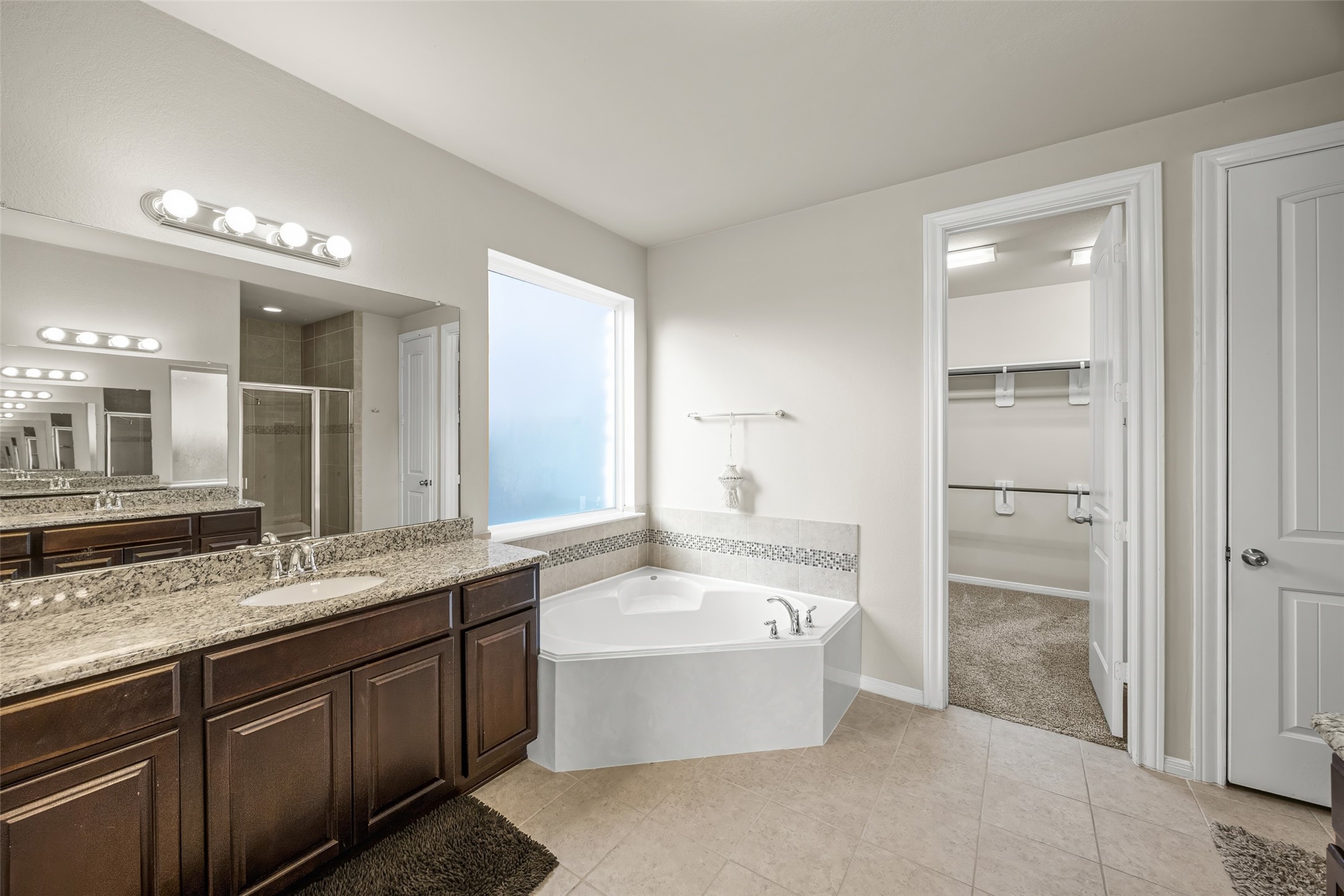 4438 Selwyn Road Richmond, TX 77407 - Photo 15 of 23 a bathroom with a bathtub a double vanity sink and mirror