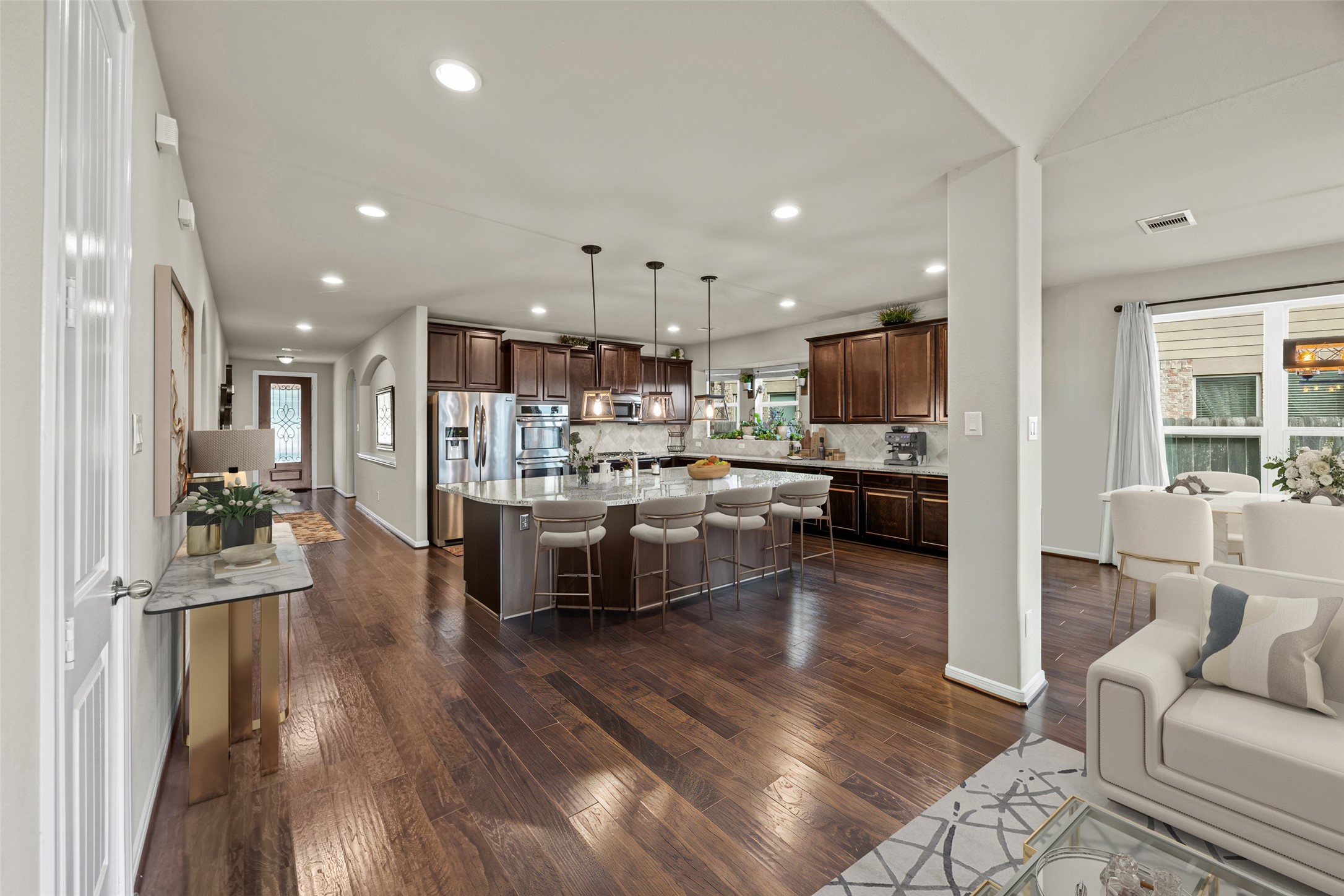 4438 Selwyn Road Richmond, TX 77407 - Photo 7 of 23 a kitchen with stainless steel appliances kitchen island granite countertop a refrigerator oven a sink a dining table and chairs with wooden floor