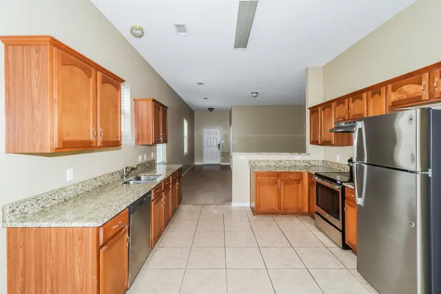 a kitchen with stainless steel appliances granite countertop a refrigerator and a stove top oven