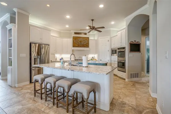 a kitchen with kitchen island granite countertop a sink a center island and stainless steel appliances