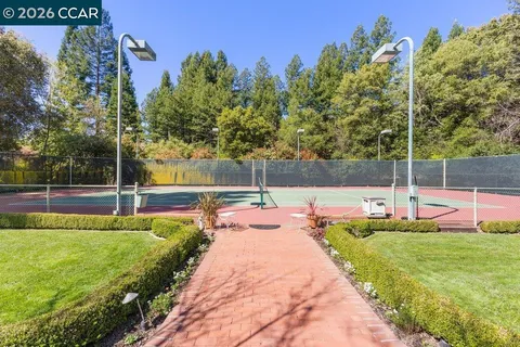 a view of a tennis ground with large trees
