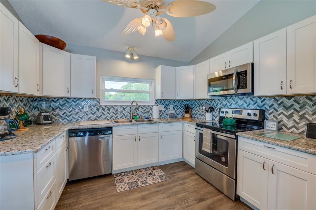 1633 Riverside Drive Daytona Beach, FL 32117 - Photo 5 of 25 a kitchen with granite countertop a sink stainless steel appliances and white cabinets