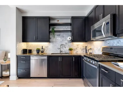 a kitchen with stainless steel appliances granite countertop a stove a sink dishwasher and a microwave oven on the granite countertops