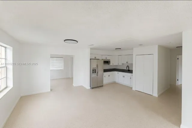 a view of a kitchen with refrigerator and white cabinets