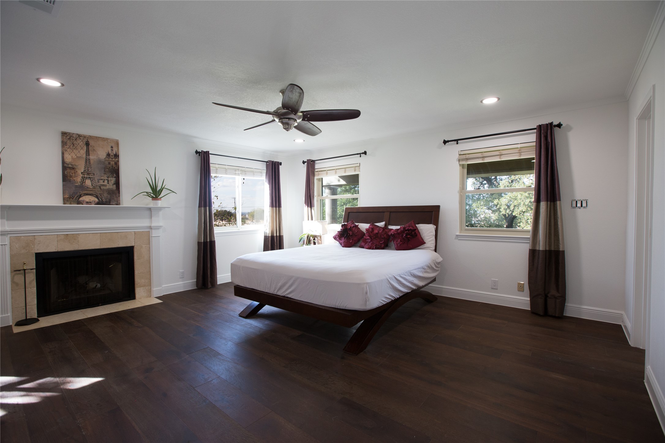3517 Gattis School Road Round Rock, TX 78664 - Photo 7 of 16 Rich hardwood floors complement this spacious bedroom, featuring a warm fireplace and multiple windows.