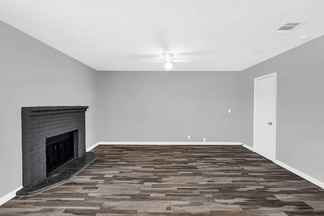 a view of empty room with wooden floor and fireplace