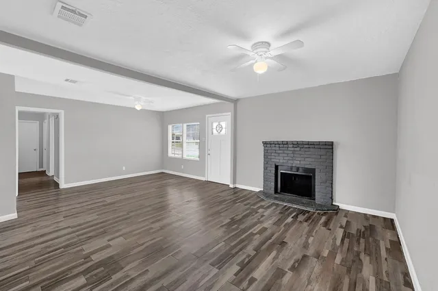 a view of an empty room with wooden floor and a fireplace