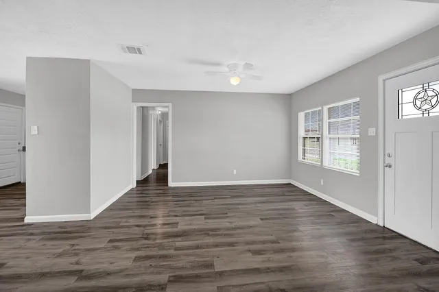 a view of an empty room with wooden floor and a window