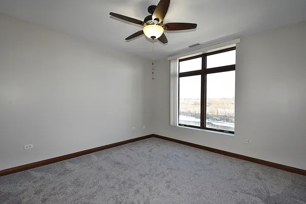 an empty room with windows and fan