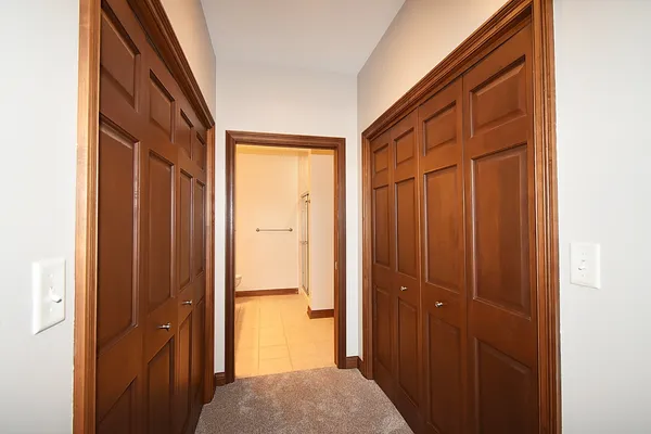 a view of hallway with closet and wooden floor