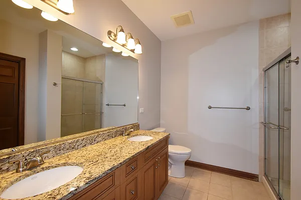 a bathroom with a granite countertop sink a toilet and shower