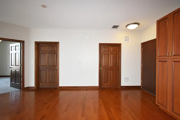 an empty room with wooden floor and closet area