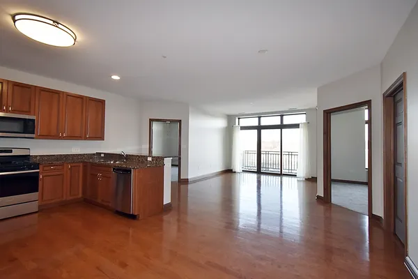 a large kitchen with stainless steel appliances granite countertop a stove top oven a sink and a granite counter tops with wooden floors