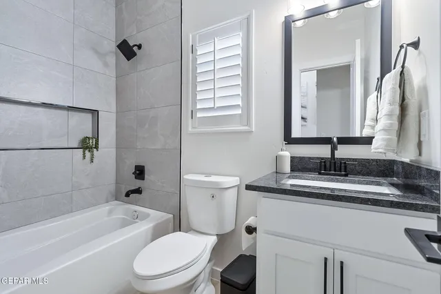 a bathroom with a granite countertop sink toilet mirror and bathtub