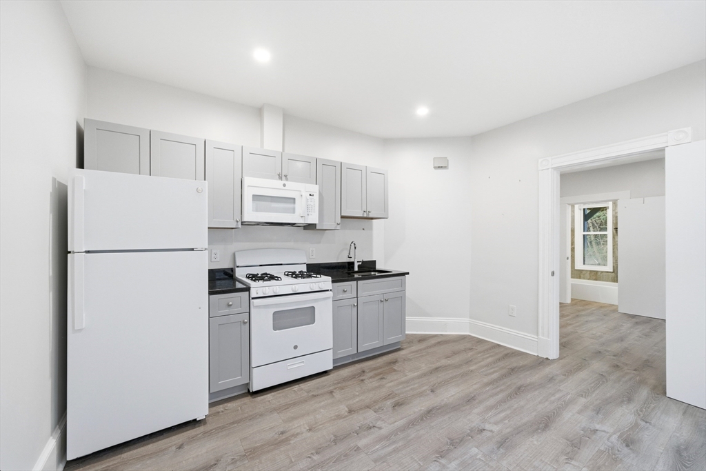 a kitchen with a refrigerator a stove top oven and white cabinets