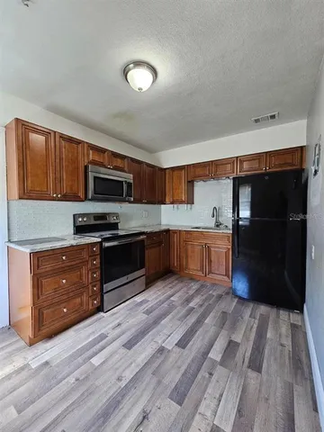 a kitchen with wooden floors and black appliances