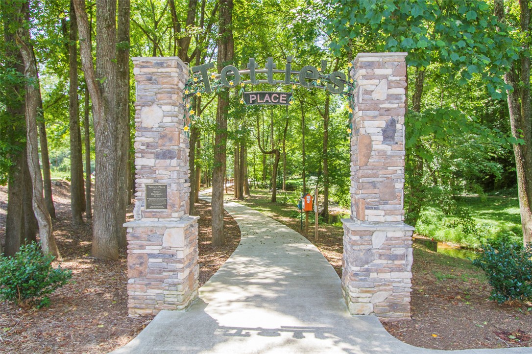 52 Hickory Way Clemson, SC 29631 - Photo 47 of 49 Enter a serene pathway framed by robust stone pillars, inviting peaceful strolls through nature.