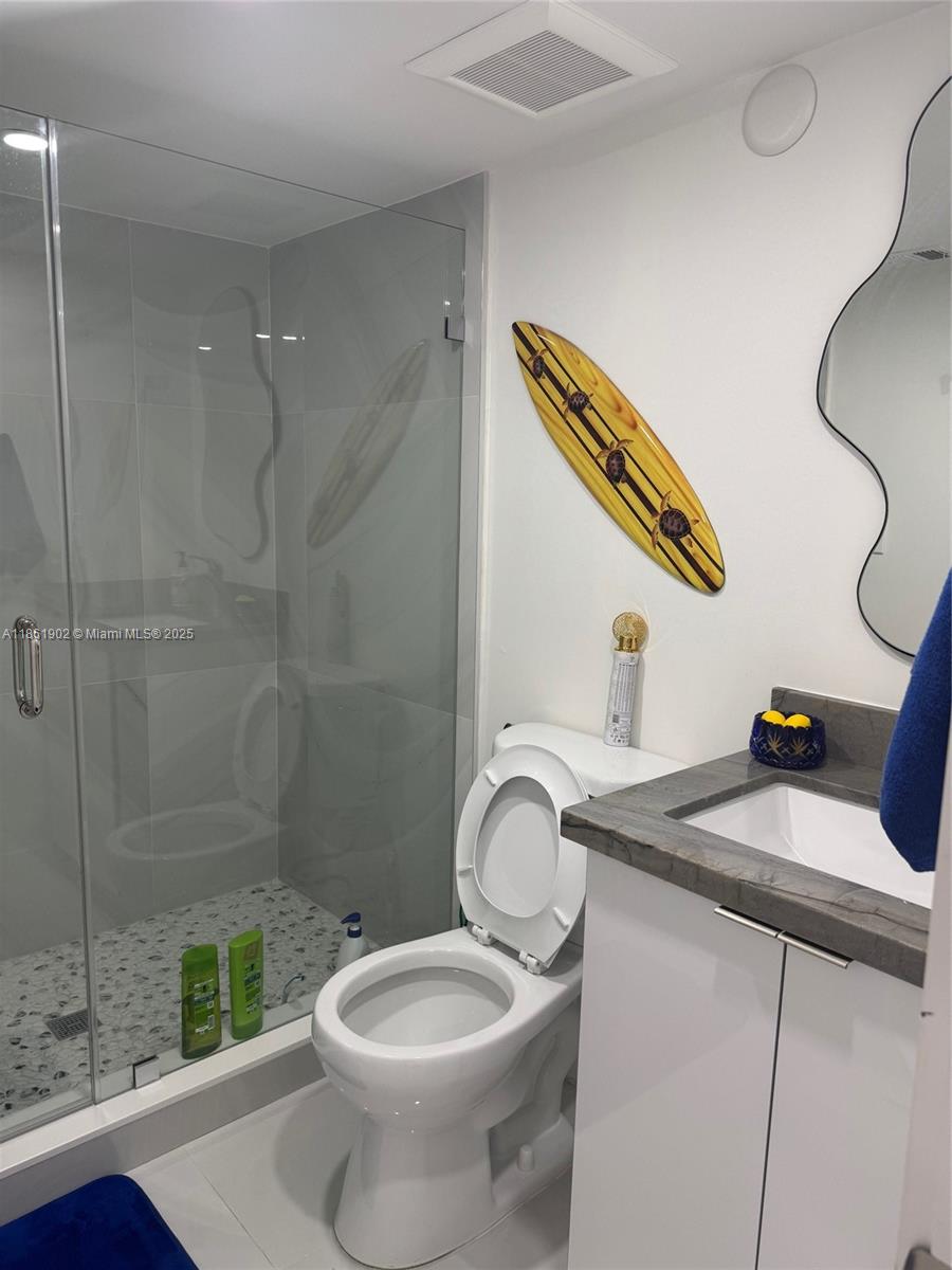 6423 Collins Avenue, Unit 401 Miami Beach, FL 33141 - Photo 3 of 17 a bathroom with a granite countertop sink a toilet and a shower