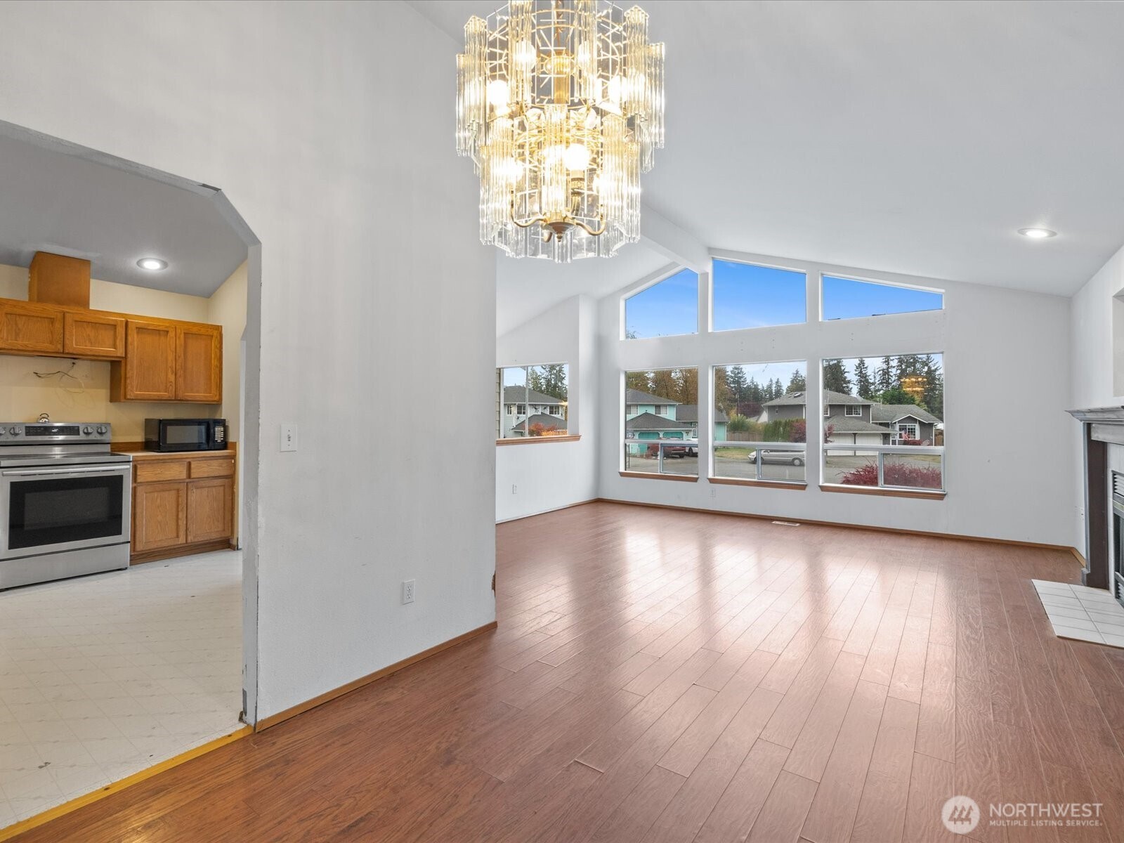 5411 158th Place Southwest Edmonds, WA 98026 - Photo 4 of 38 an empty room with wooden floor kitchen view and windows