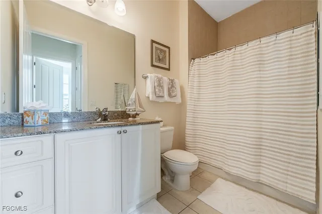 a bathroom with a granite countertop toilet a sink a mirror and a shower