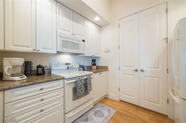 a kitchen with granite countertop white cabinets and white appliances