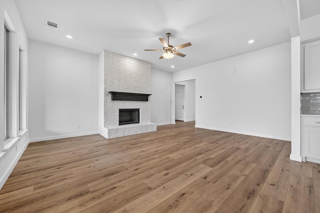 416 McAlpine Drive Springtown, TX 76082 - Photo 10 of 40 Spacious room featuring wood-finish flooring, a white brick fireplace with a dark mantel, recessed lighting, a ceiling fan, and large windows