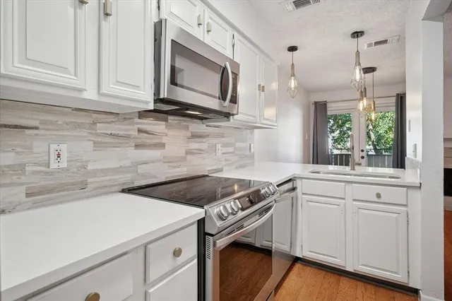 a kitchen with granite countertop white cabinets stainless steel appliances and a sink