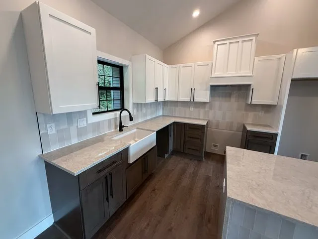 a kitchen with kitchen island granite countertop a sink stove and cabinets